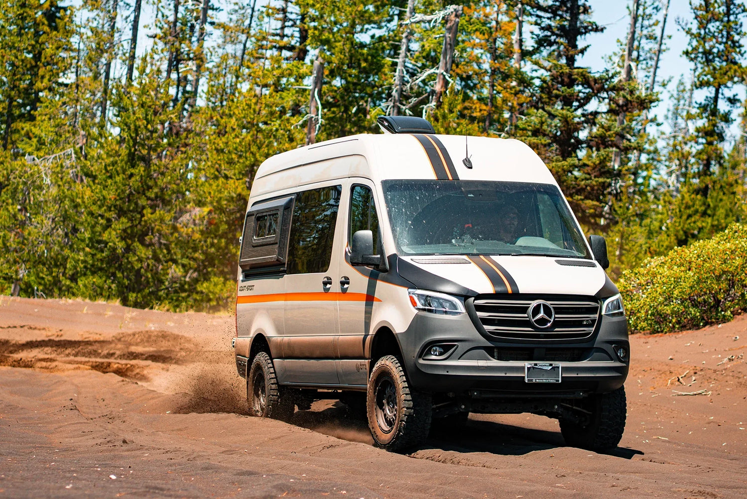 Adapt‑Sport Sprinter adventure van by Otzivans parked off‑road in the mountains, ready for a camping trip.