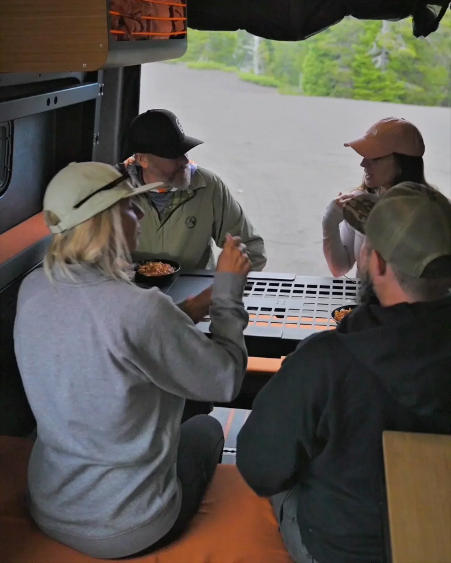 Adapt‑Sport Sprinter interior showing the Otzivans Lifestyle Bed System configured as a rear lounge with seating and table inside the adventure van.