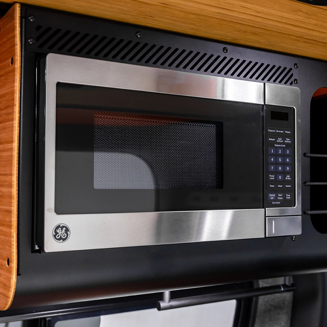 Overland camper van and camp chairs arranged under the awning at a quiet lakeside camping spot