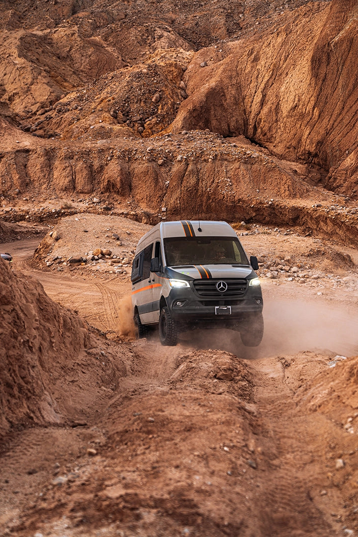 Off‑grid camper van sleeping area with thick mattress, built‑in shelves, and insulated walls for four‑season camping