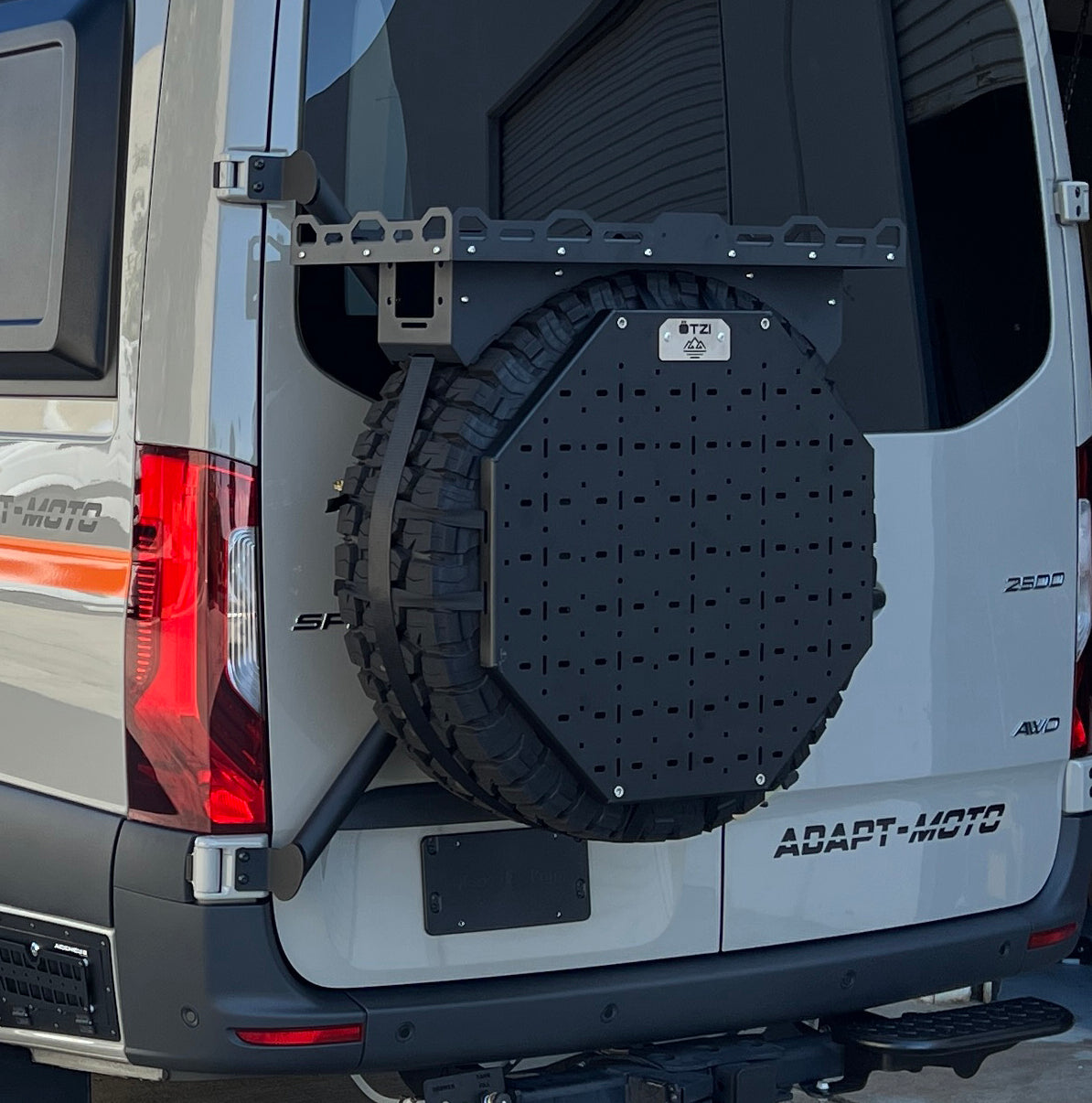 Rear view of a van with a mounted spare tire carrier and utility panel.