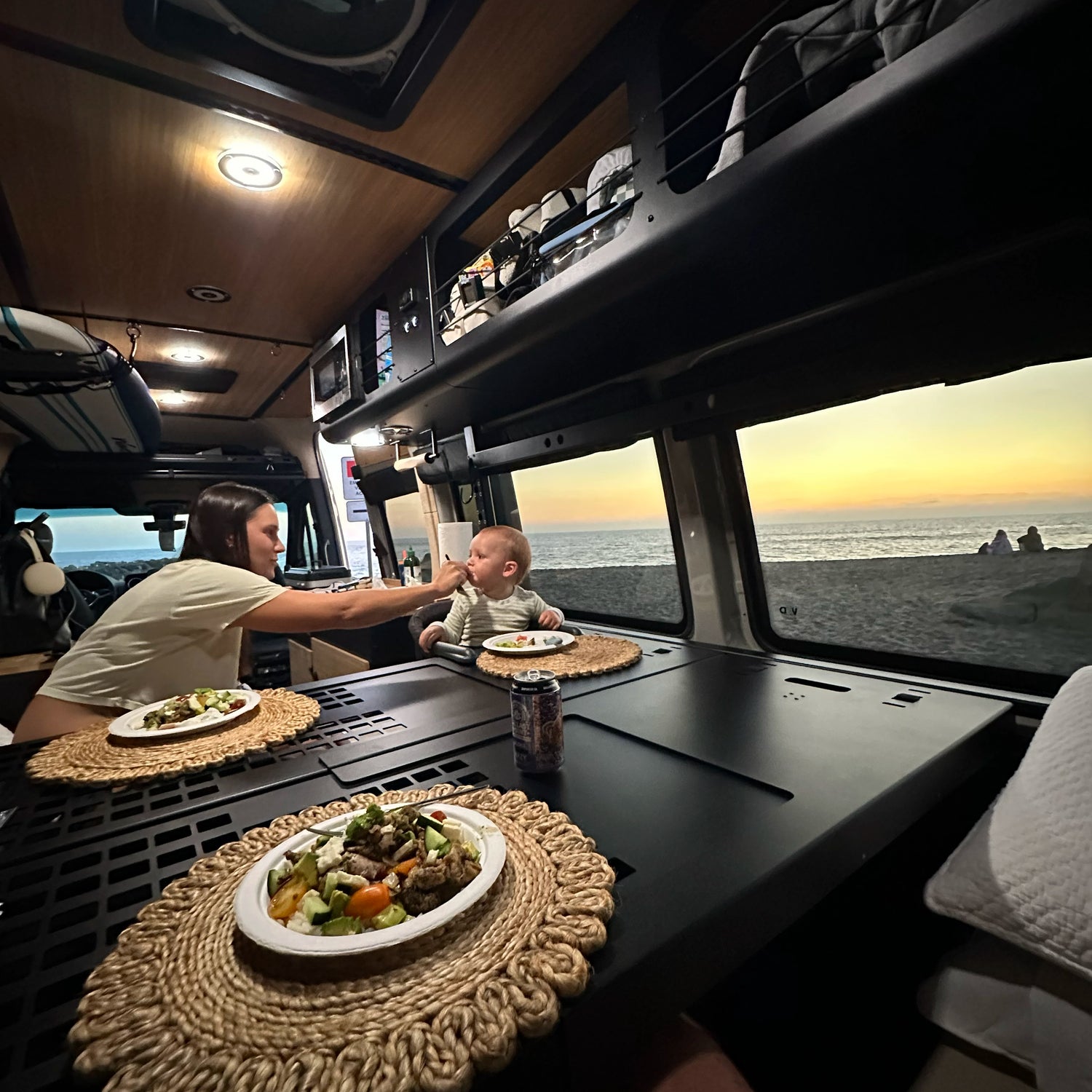 Minimalist vanlife bed setup inside an off‑road camper van, with gear stored neatly under the platform