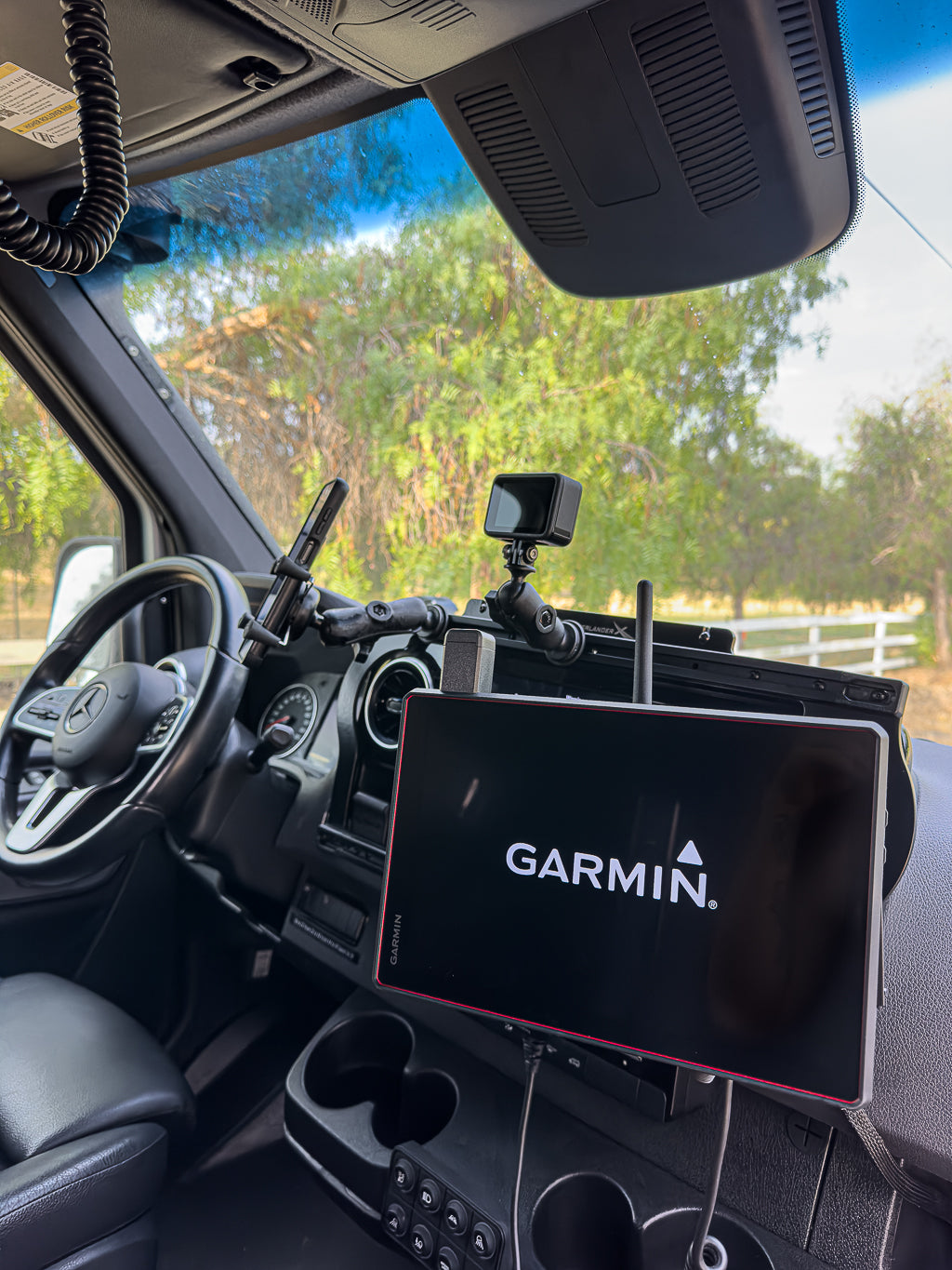 Garmin GPS device mounted on a Mercedes-Benz van dashboard with steering wheel and camera visible