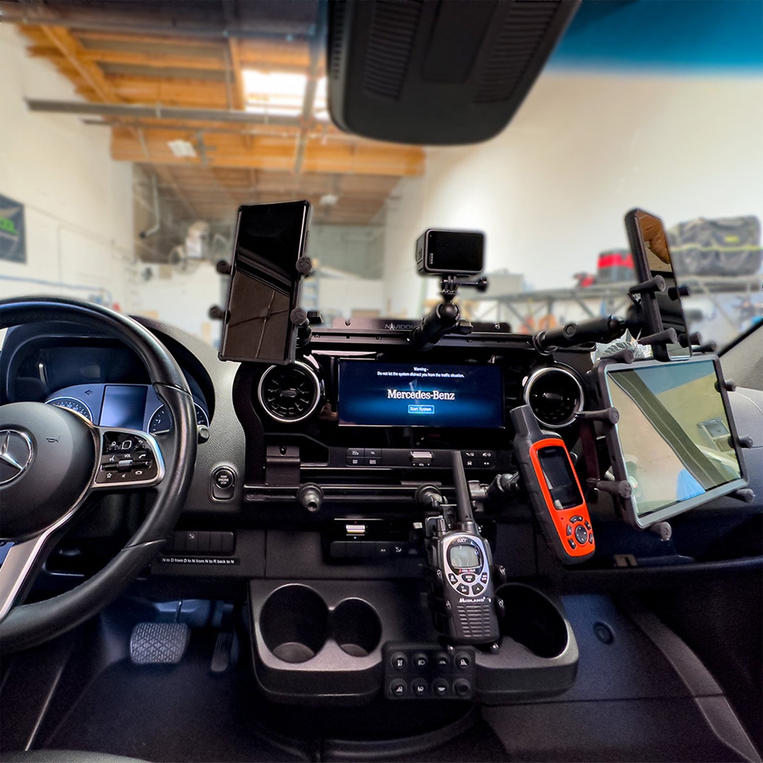 Car dashboard setup with mounted devices including radios, phones, a tablet, and a GPS unit.