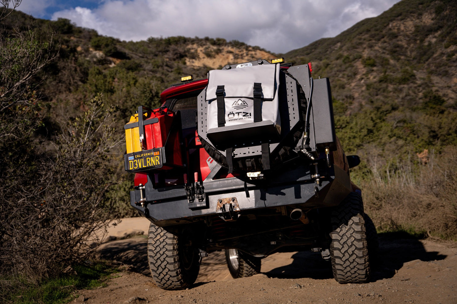 Rear view of an off-road vehicle with mounted backpacks and gear on a dirt trail