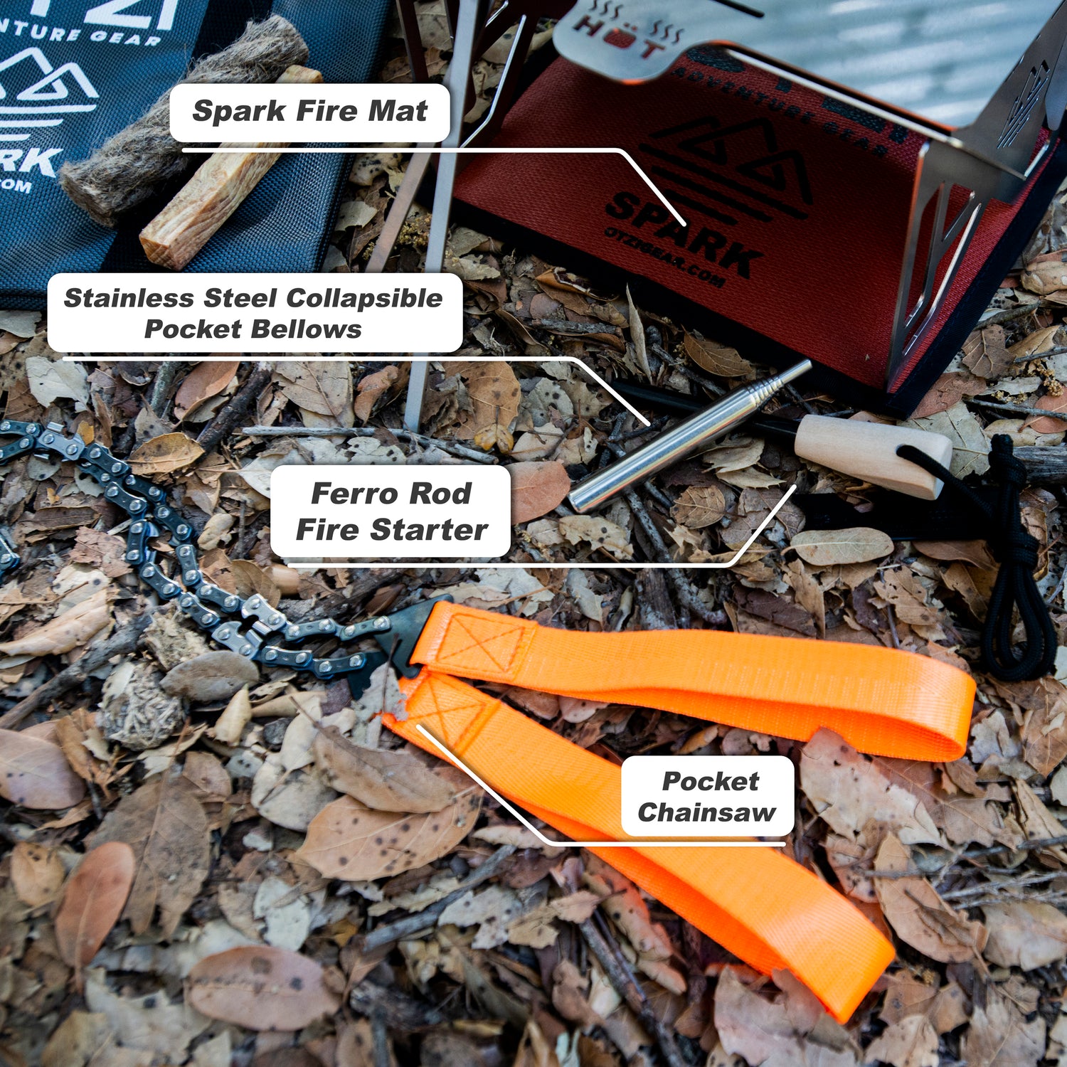 Camping fire starting kit with spark mat, pocket bellows, ferro rod, and orange pocket chainsaw on forest floor.