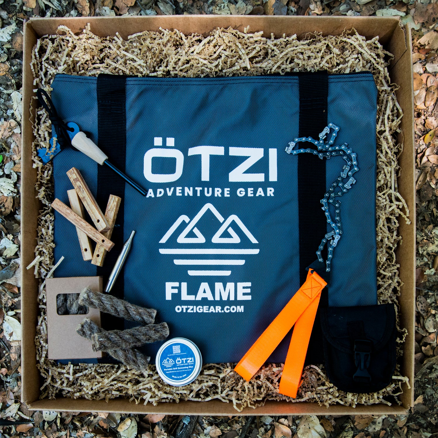 Outdoor fire starter kit with carrying case, flint striker, folding saw, firewood sticks, and accessories.