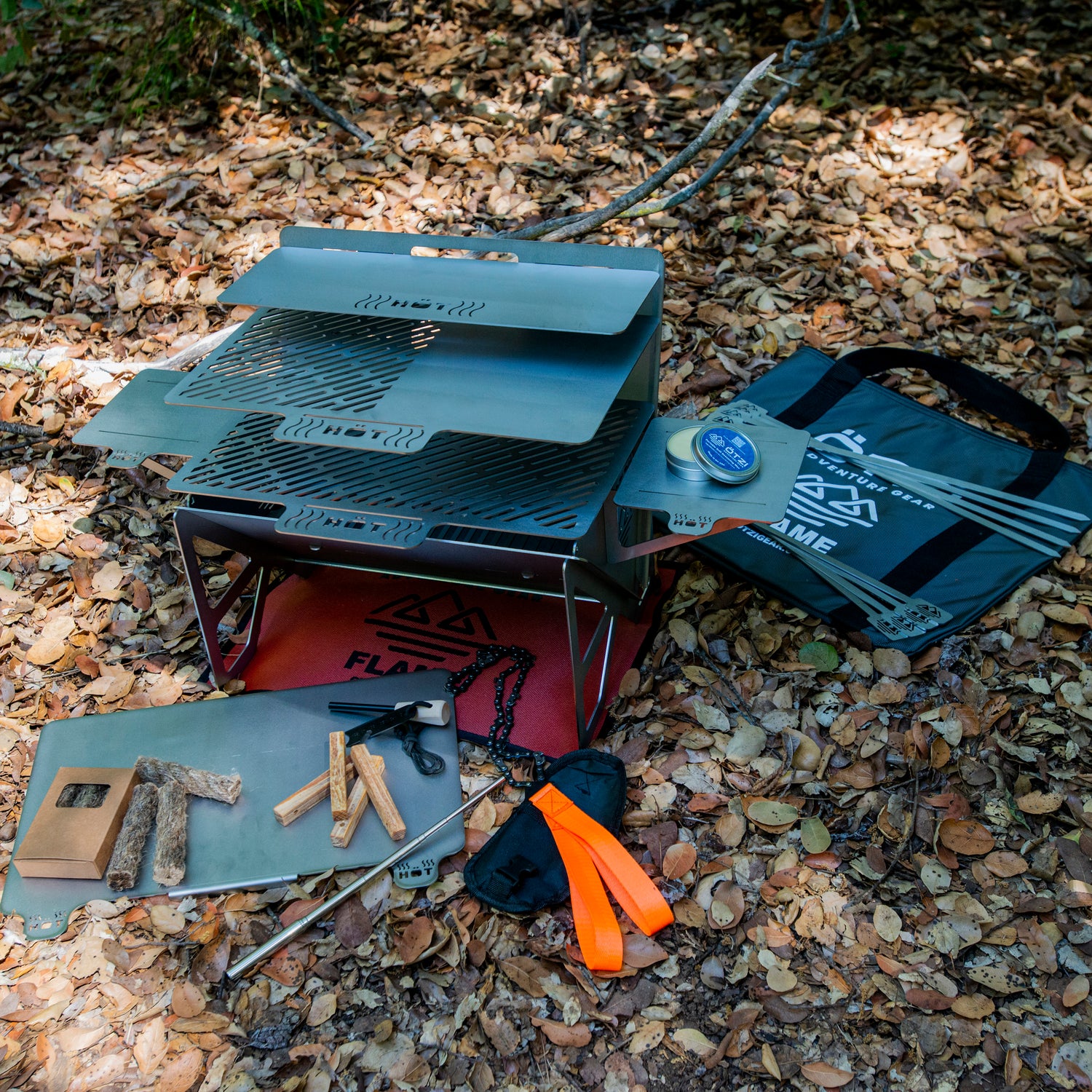 Portable stainless steel camping grill set with accessories on forest floor