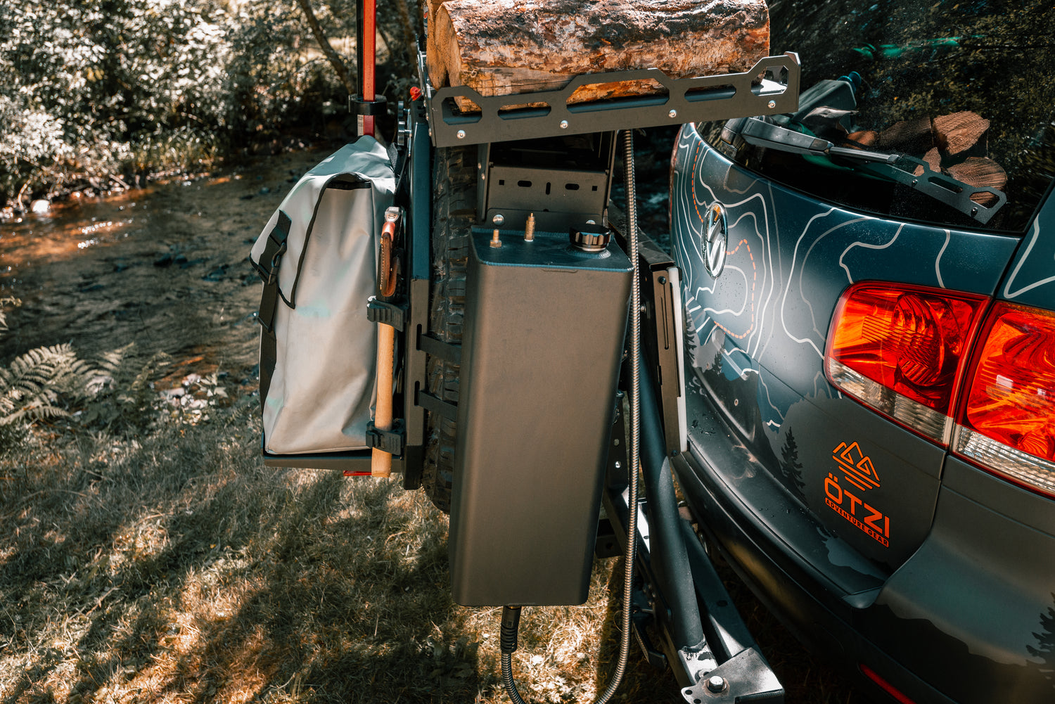 Rear-mounted camping storage and gear system attached to SUV with firewood and equipment.