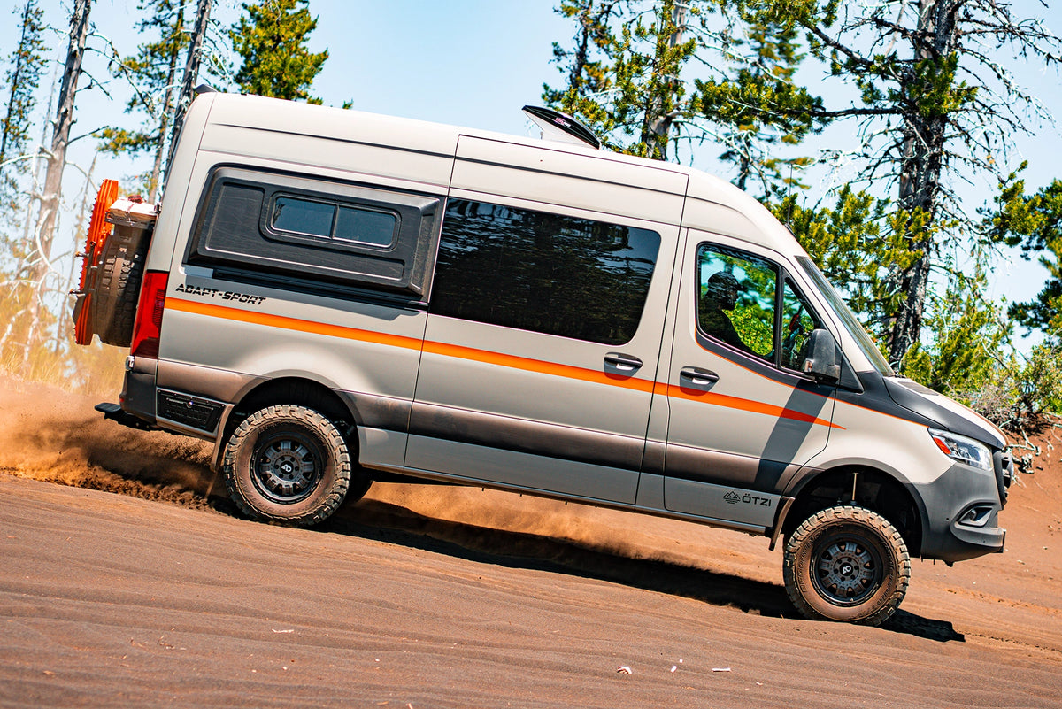 Silver Otzi adventure van driving on a forest dirt road