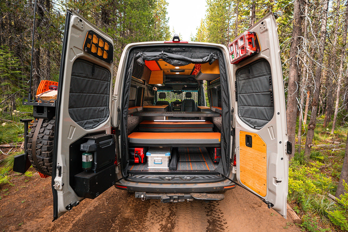 Open rear doors of an Otzi van showing its raised bed and gear storage