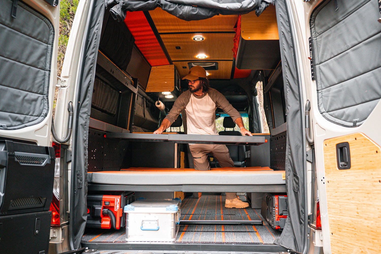 Adventure van with more garage storage than camplife customs with bikes, water tanks, and slide‑out gear trays under raised bed