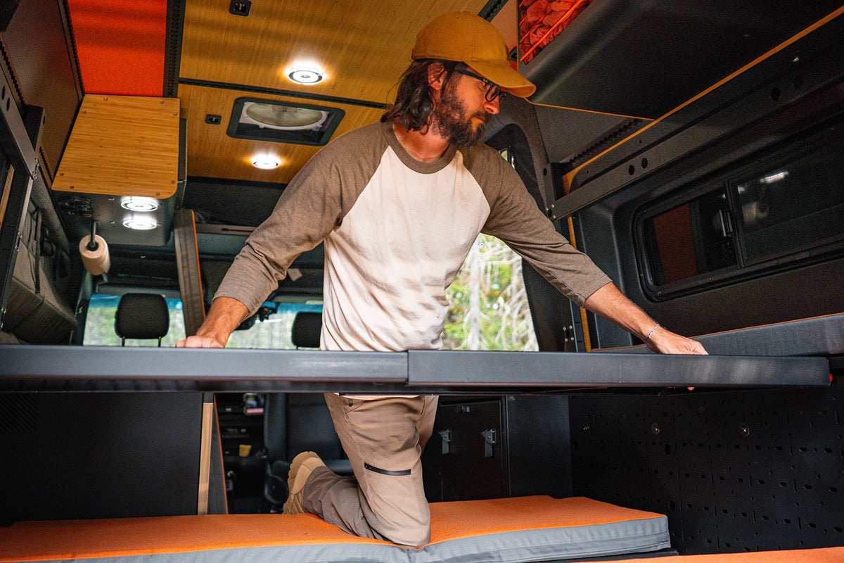 Person adjusting a bed platform inside an Otzi adventure van