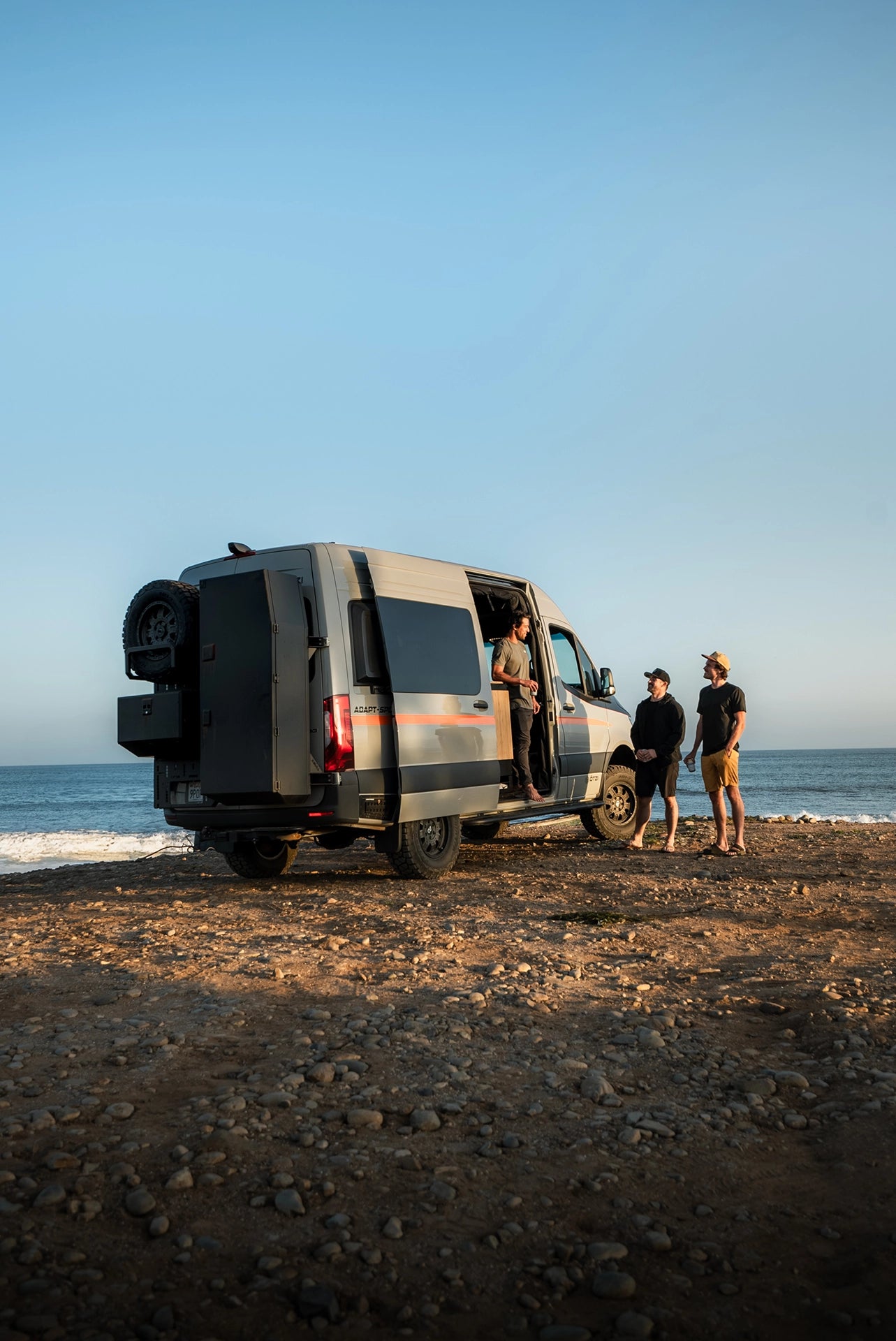 Family relaxing outside an off‑road camper van, experiencing vanlife at a remote boondocking site