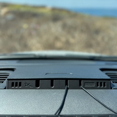 Dashboard-mounted charging station with two connected cables, viewed from inside a car.
