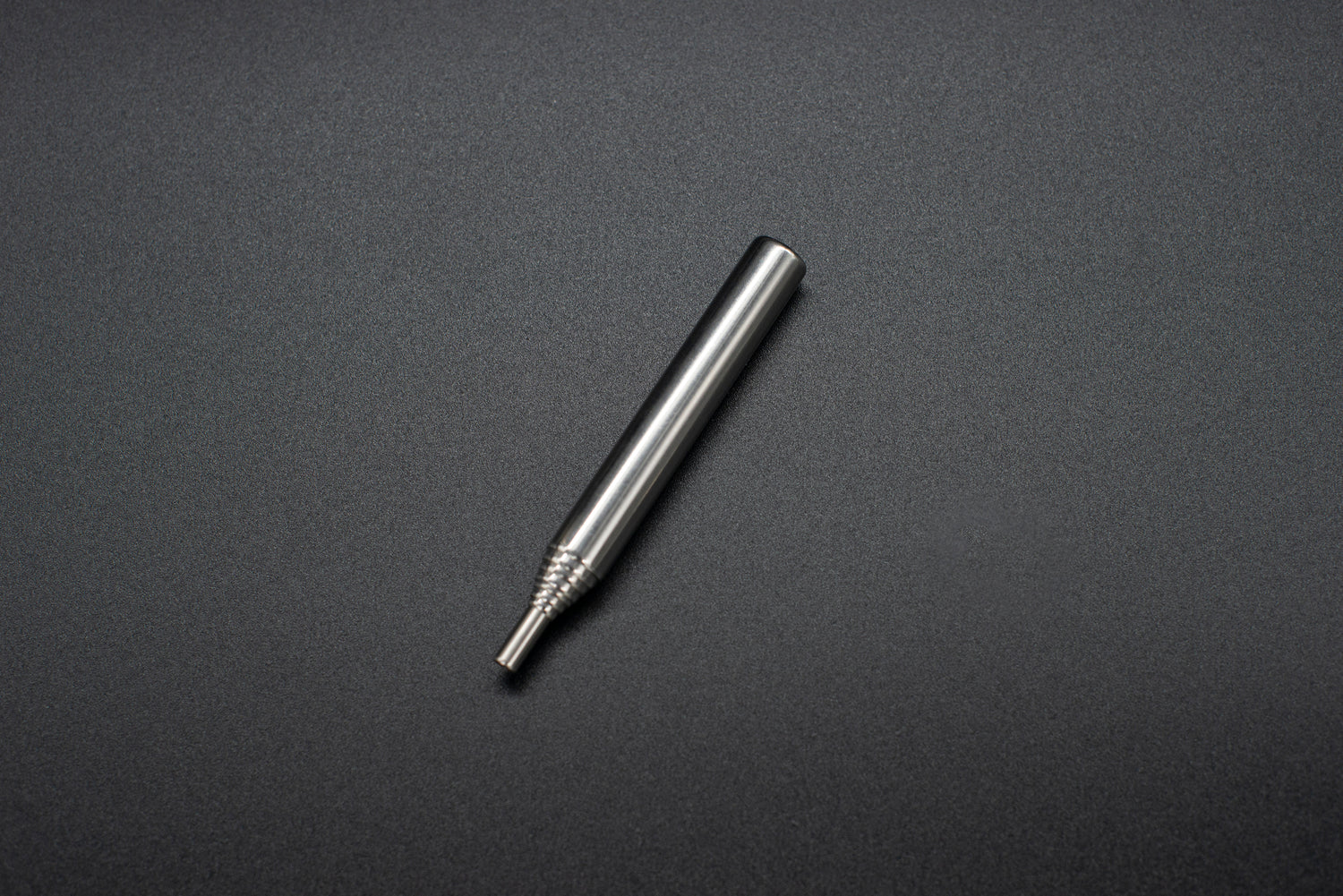 Stainless steel one-hitter pipe with textured grip on a dark background