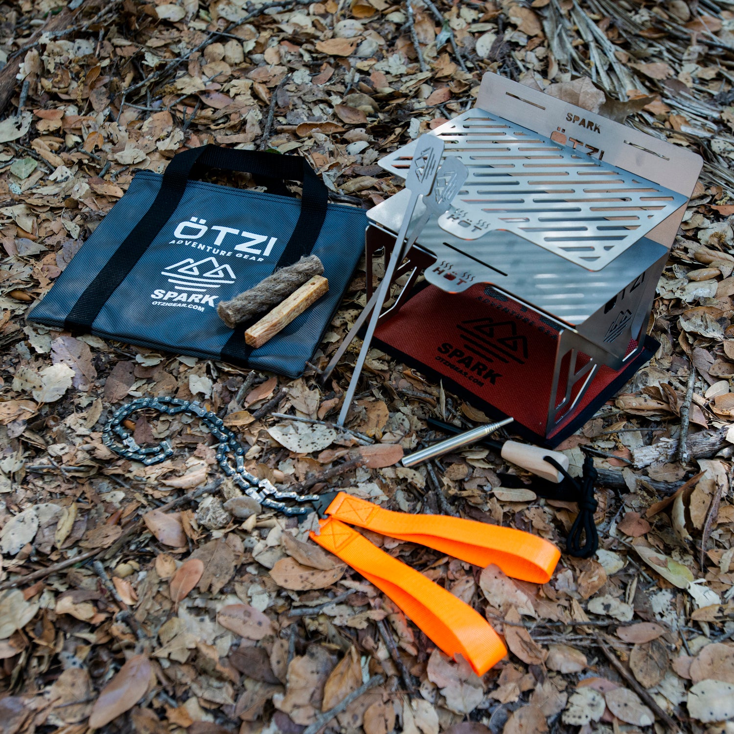 Portable camping grill set with fire starter and carrying case on forest ground.