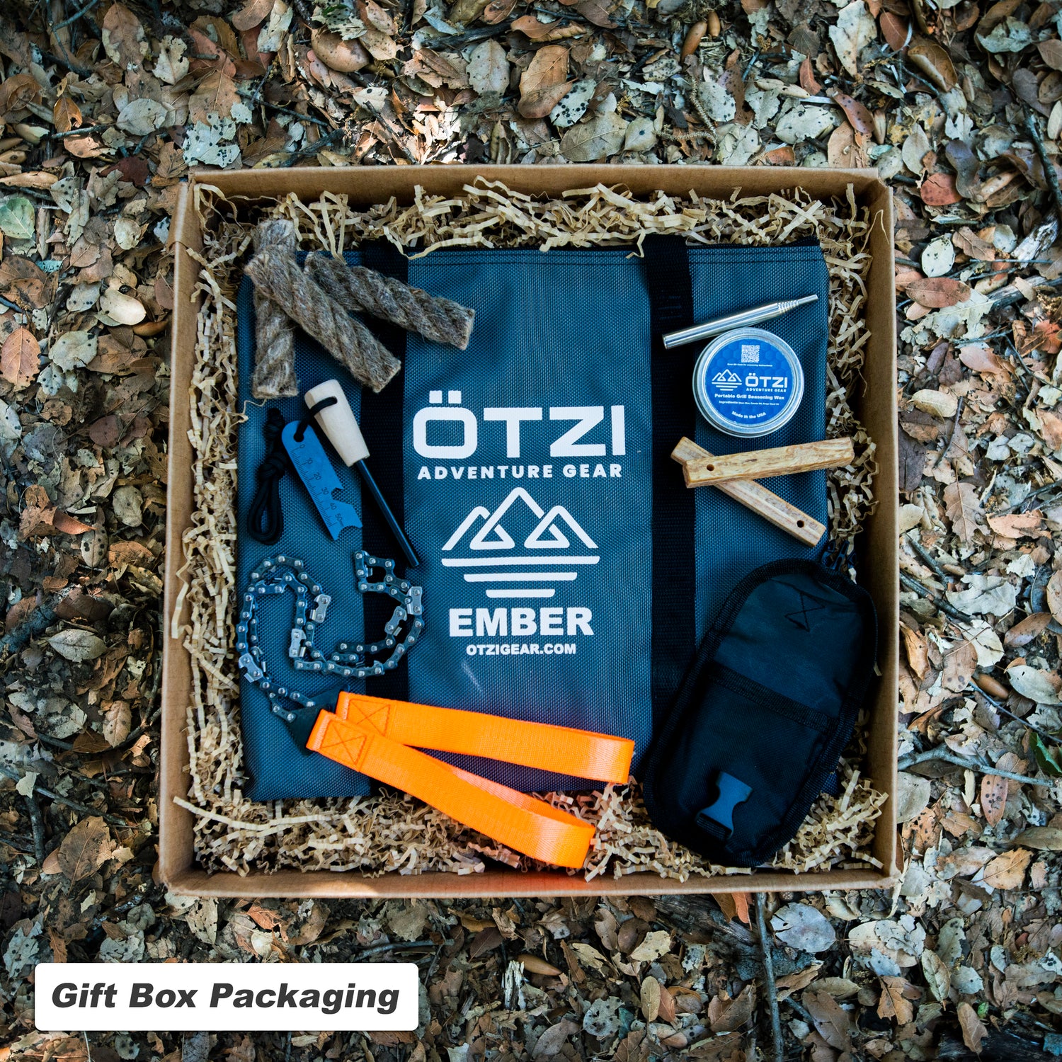 Outdoor adventure gear gift box with tools, fire starters, and accessories on shredded paper.