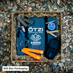 Outdoor adventure gear gift box with tools, fire starters, and accessories on shredded paper.
