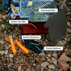 Outdoor fire kit with fire mat, pocket chainsaw, bellows, and seasoning wax on leaves.