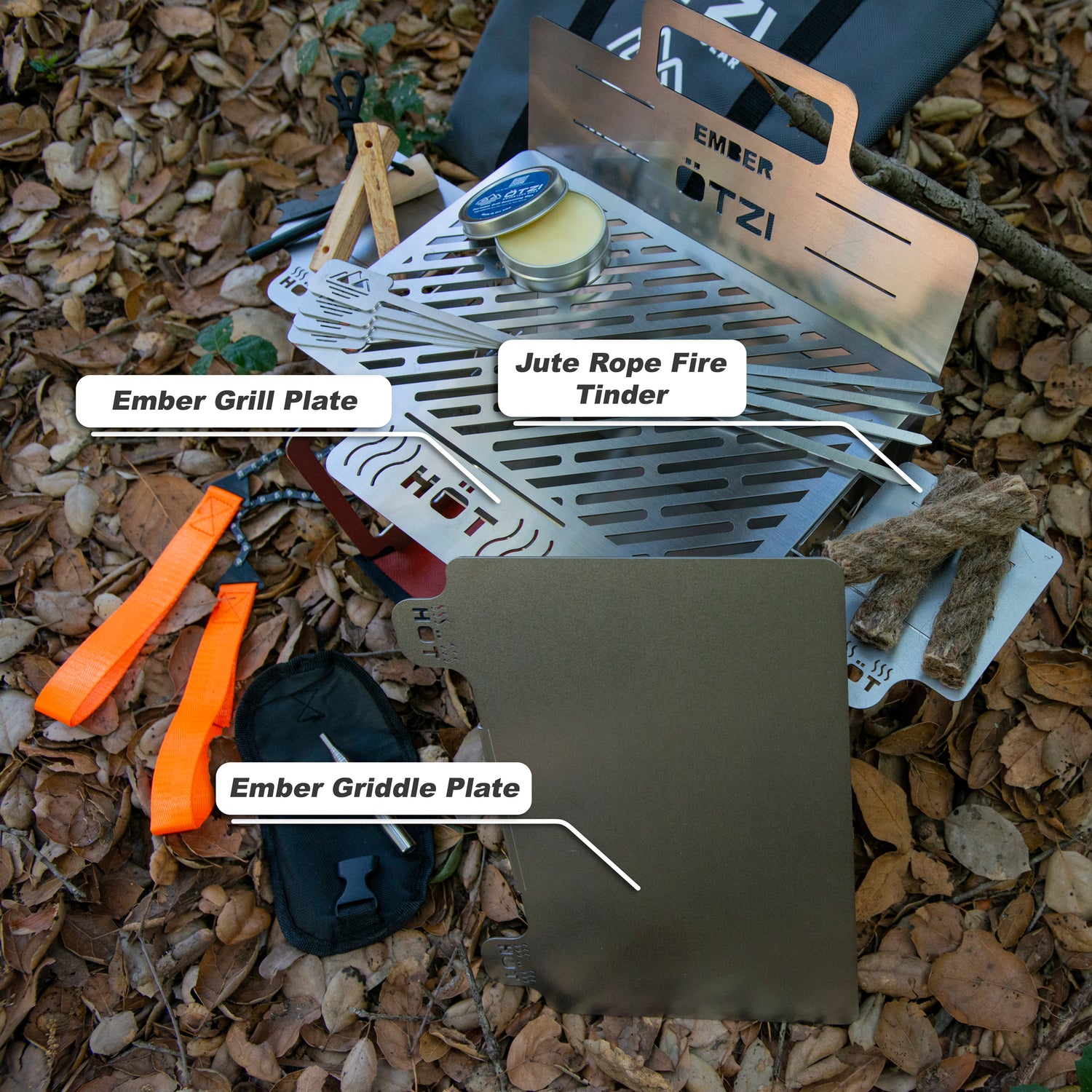 Outdoor cooking kit with Ember grill and griddle plates, jute fire tinder, tools, and accessories on forest floor