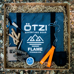Outdoor fire starter kit with carrying case, flint striker, folding saw, firewood sticks, and accessories.