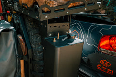 Close-up of a mounted fuel canister and gear tools on an off-road vehicle.