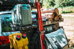 Off-road vehicle cargo rack loaded with firewood, fuel cans, water container, and gear bags