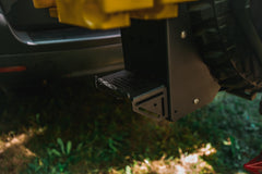 Close-up of a black metal hitch-mounted accessory attached to a vehicle rear bumper