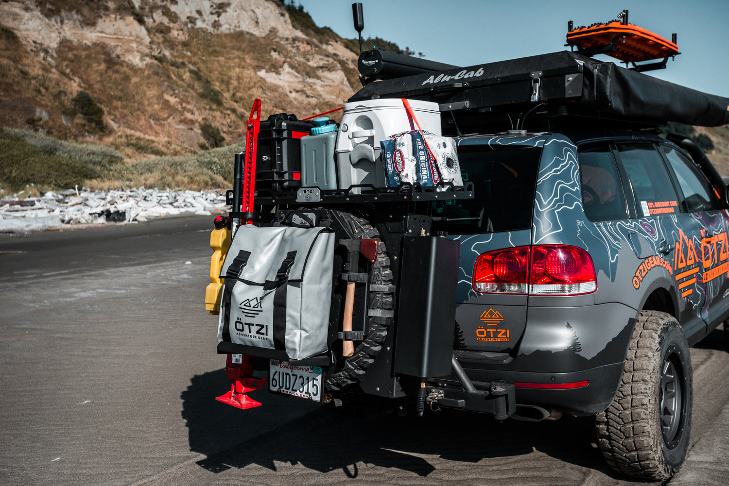 SUV equipped with overlanding gear including water containers, storage bags, and recovery tools