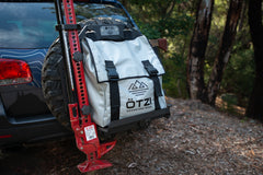 Ötzi adventure gear bag mounted on a spare tire rack at the back of an off-road vehicle.