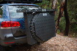 Vehicle-mounted tire carrier with modular storage rack in a wooded area