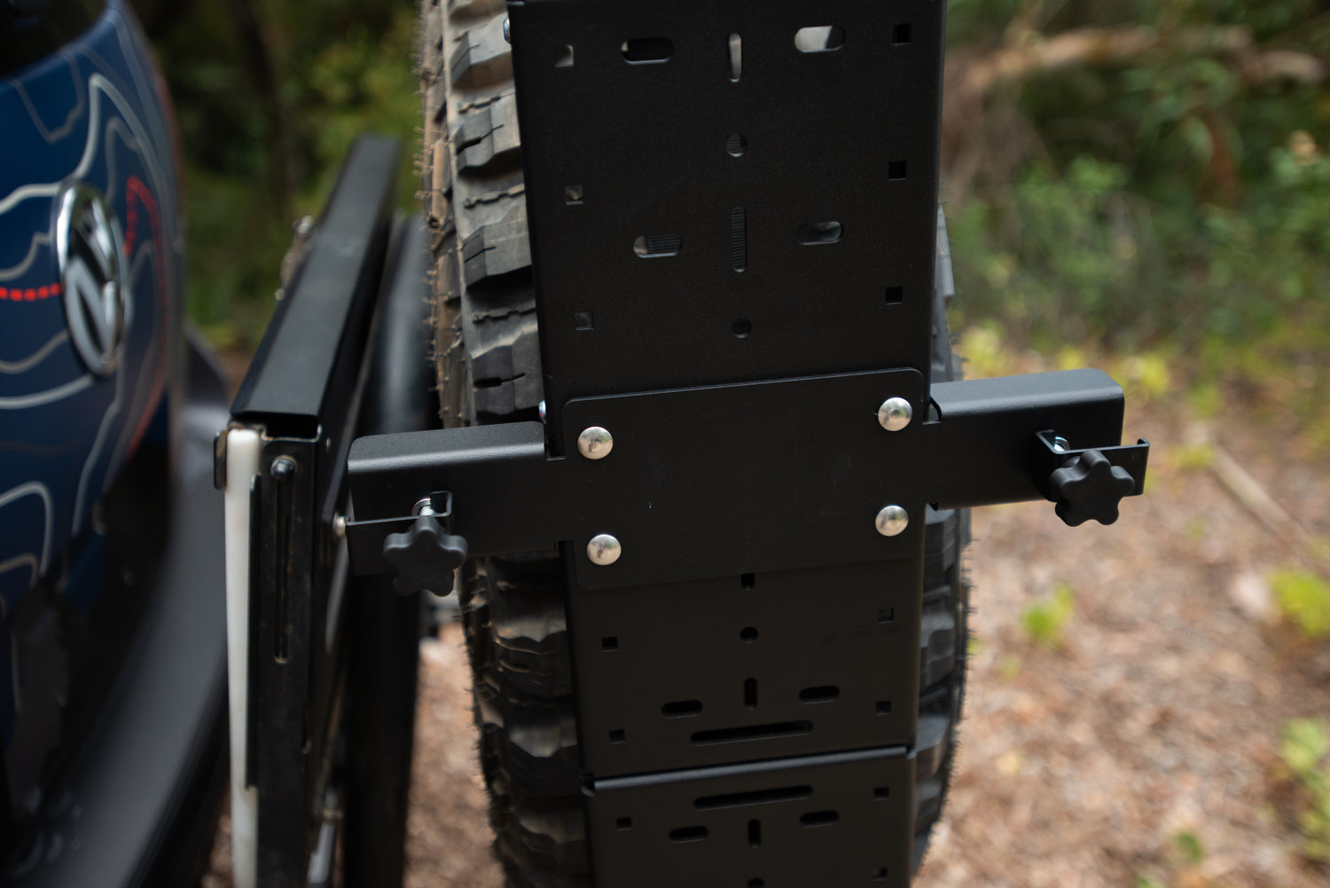 Close-up of a spare tire mounted on a rear swing-out tire carrier on an off-road vehicle.