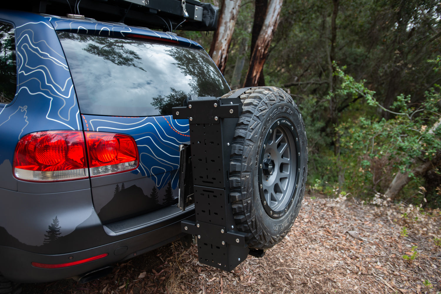 SUV with rear-mounted spare tire carrier in a forest setting