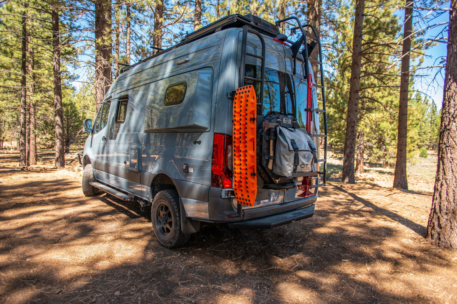 Off-road camper van parked in a forest with gear mounted on the rear door
