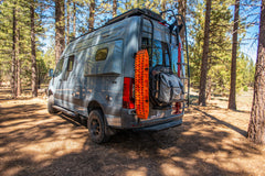 Off-road camper van parked in a forest with gear mounted on the rear door