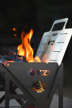 Stainless steel portable fire pit with flames and visible OTZI branding
